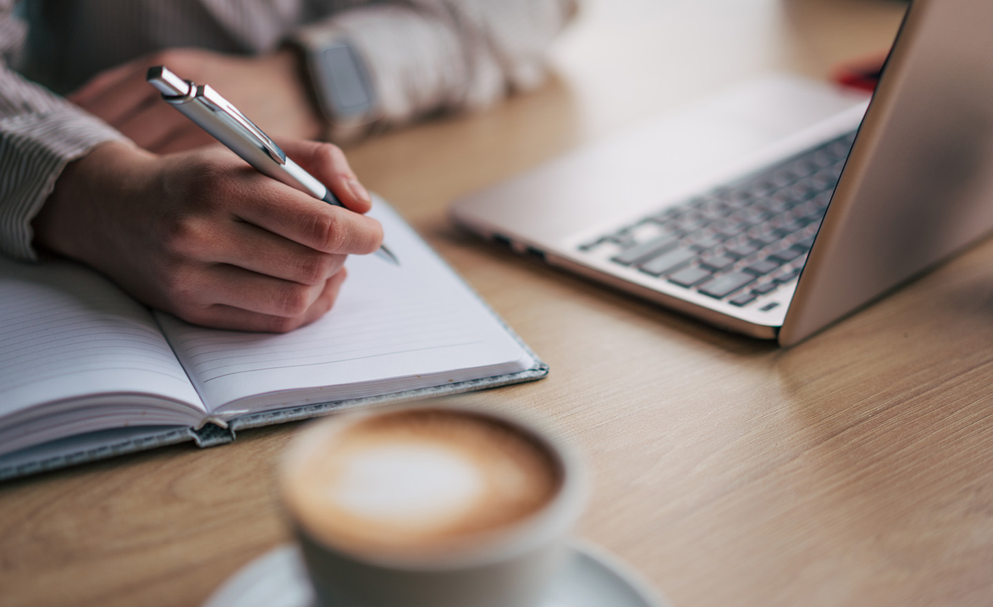 Coffee, notebook and laptop representing Leatherhead Food Research's online regulatory training courses