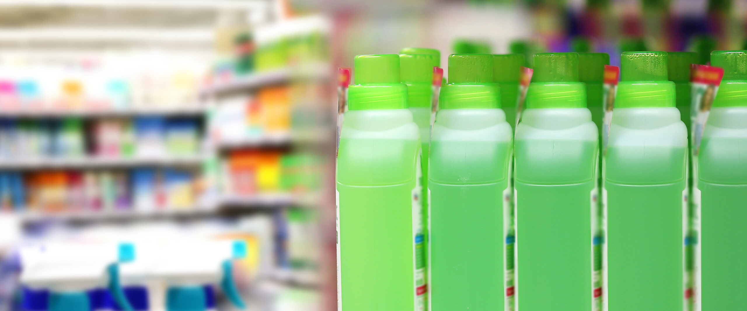 Row of bright green bottles with green caps lined up in a store aisle, blurred shelves in the background.