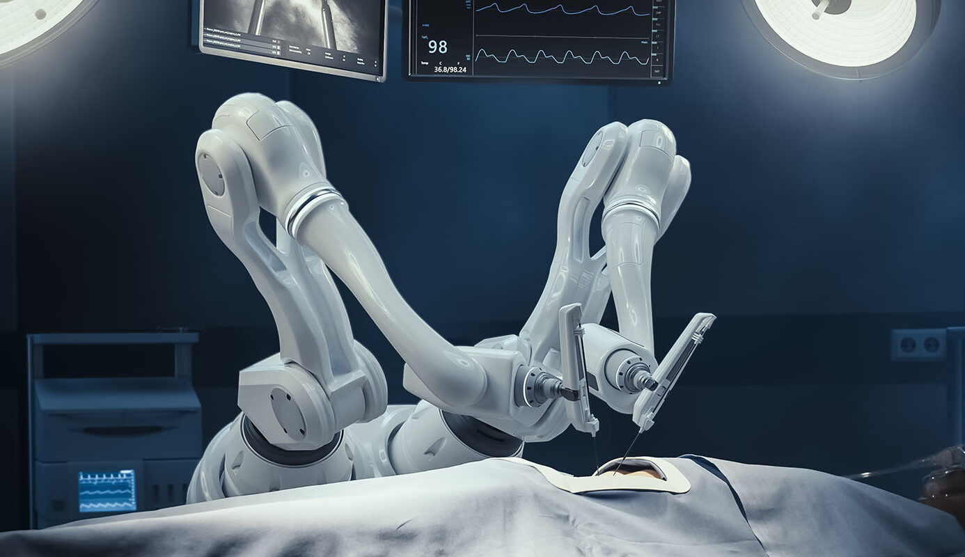 Robotic surgical arms operating on a patient in an illuminated operating room with monitors overhead.