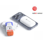 Smartphone with a white curved back accessory attached, a blue/orange device nearby, on a white surface; ‘red dot winner 2026’ logo visible.